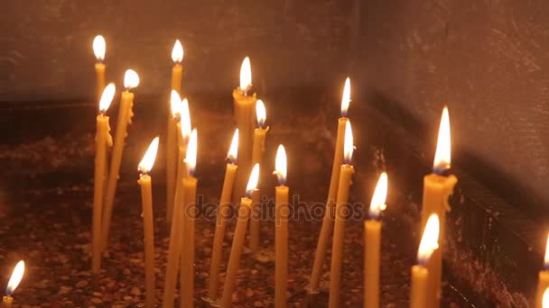 Encender una vela con una cerilla para conseguir una vela romántica. Increíbles andles y candelabros están sobre la mesa. Mantenga las luces con el trasfondo pacífico de la ceremonia religiosa . — Vídeo de stock