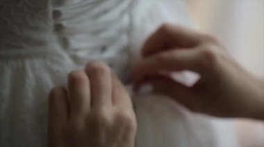 Günaydın gelin. Baş nedime geline elbisesinde yardım ediyor. Gelinler elbiseyi bağlar. Nedime gelinliği bağlıyor. Kadın eli, gelinlerin korsesine ipek kurdele bağlar. Bağcıkları bağlamama yardım et.