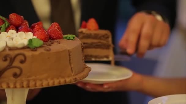 Τα χέρια της νύφης και του γαμπρού, κόψτε μια φέτα μια γαμήλια τούρτα. Κόψτε την γαμήλια τούρτα. Οι άνθρωποι κοπεί και τοποθετήστε την τούρτα σε ένα πιάτο. Λευκή σοκολάτα και κέικ. Γιορτή Knife.Wedding. — Αρχείο Βίντεο