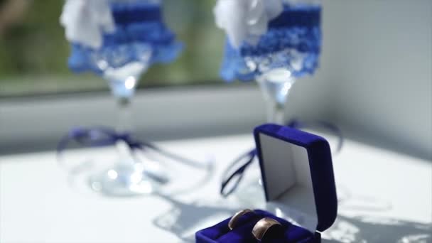 Wedding rings and wedding wine glasses on the table in the morning of the wedding day. — Stock Video