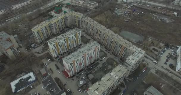 Aerial survey na miasto. Widok z nieba na rosyjskie miasto. Miasto z lotu ptaka widok na domy, ulice i parki. Szare niebo i garaże naprawdę mieszkaniowej dzielnicy. Aerial survey na ulicy gdzie jeździć dużo — Wideo stockowe