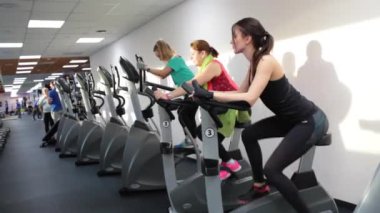 Bir grup insan kardiyo egzersizi yapıyor onların bacaklar egzersiz dört salonunda. Farklı yaş eğitim üzerinde pozitif kadın Bisiklet birlikte modern fitness kulübünde egzersiz. Weman kondisyon bisikletleri üzerinde