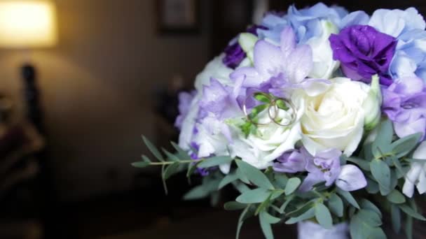 Trauringe an einem Strauß weißer Blumen. Trauringe und Strauß dunkelblauer Blume. Nahaufnahme. Hochzeit — Stockvideo