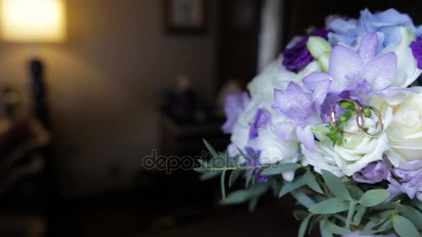 Βέρες σε μια ανθοδέσμη από λευκά άνθη. Βέρες και ανθοδέσμης των σκούρο μπλε λουλούδι. Κοντινό πλάνο. Γάμος — Αρχείο Βίντεο