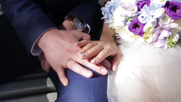 Recién casados parejas manos con anillos de boda. Novia y novio con anillos de boda en flores o ramo de bodas. Recién casados parejas manos con anillos de boda — Vídeo de stock