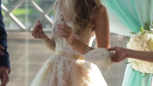 Primo piano di una sposa che mette una fede nuziale d'oro sul dito dello sposo. fedi nuziali e mani di sposa e sposo. giovane coppia nuziale a cerimonia. sposa indossare anello su sposi dito . — Video Stock