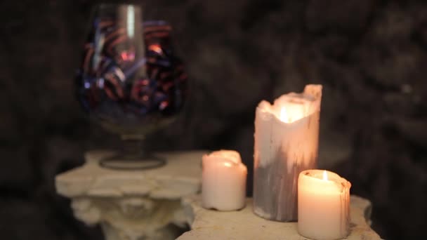 Vaso de vidro com chocolates e doces e velas em chamas em primeiro plano. Doces de chocolate em um vaso e velas ardentes. Doces de chocolate e doces num vaso. Velas — Vídeo de Stock