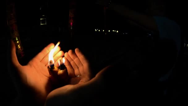 Зажигание свечей в буддийском храме ночью. Мужские руки на огне красные большие свечи в храмовой гопро. Красная свеча в китайском храме. Увольте от первого лица. Тайский храм — стоковое видео