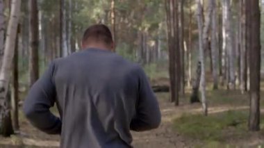 Ormanda görünümü aracılığıyla bir doğa iz boyunca arkadan çalışan erkek atlet. bir yaz orman yoluyla vücut parçası geri çalışan erkek atlet. Sonbahar orman içinden çalışan yalınayak erkek