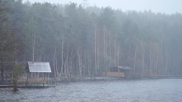 Pier at the lake, forest lake shore rain and snow. The mirror surface of the lake, the forest is covered with the first snow. reflection in the water, a beautiful mountain landscape. tree fallen in — Stock Video