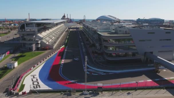 A pista de fórmula 1 em Sochi, a vila olímpica de Sochi. Local de construção do estádio para corridas perto da cidade e montanhas no dia ensolarado de verão. Vista aérea. Vista aérea sobre peitoril stands F1 russo — Vídeo de Stock