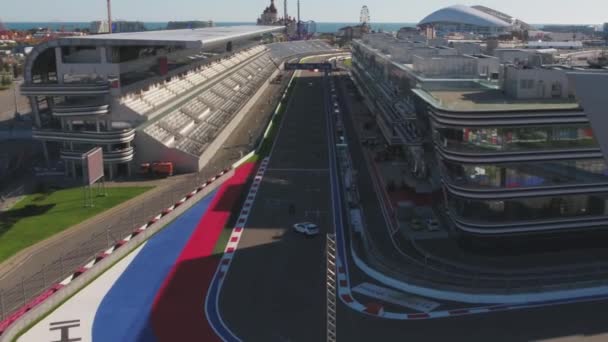 La piste de formule 1 à Sotchi, le village olympique de Sotchi. Site de construction du stade pour la course près de la ville et des montagnes par une journée ensoleillée d'été. Vue aérienne. Vue aérienne sur les stands de pectateur F1 Russe — Video