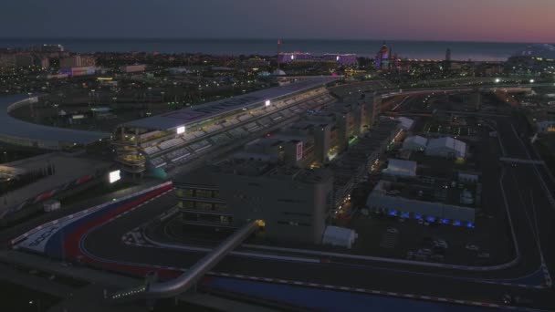 VILAGE OLIMPIQUE AÉRIEN, SOCHI, RUSSIE. Le village olympique de Sotchi la nuit. Incroyable perspective de fantastique hôtel Bogatyr, la piste de formule 1, le stade fischt, bâtiment rétroéclairé par différents — Video