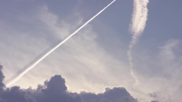 大型客机超音速飞机飞得很高在湛蓝的天空，留下长长的白色痕迹。飞机在湛蓝的天空上留下对角跟踪。喷气式飞机在蓝天上一长串 — 图库视频影像