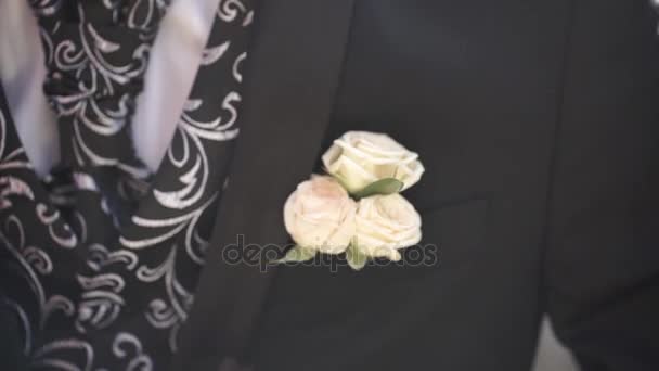Flor de cravo em um bolso. a flor no bolso do casaco. alfinete com flores brancas decorativas presas na jaqueta dos noivos. flor boutonniere no bolso do noivo na cerimônia de casamento — Vídeo de Stock