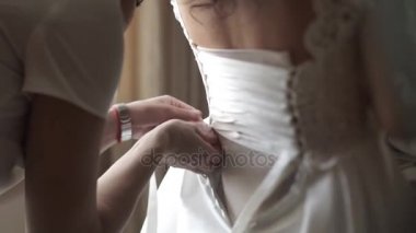 Beyaz elbiseli güzel esmer gelin yardım şık güzel nedime düğün, sabah hazırlıklar, kadın elbise koymak için hazır olun. Anne ve gelinin nedimesi, yardım için bir gelinlik elbise