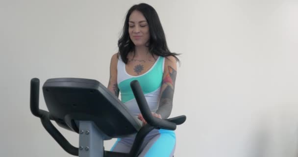 Tres hermosas mujeres jóvenes haciendo ejercicio en las bicicletas en el gimnasio. Mujer joven activa haciendo ejercicio en bicicleta estática bicicleta estacionaria. Entrenamiento de chica deportiva en el gimnasio, gimnasio. Chica en bicicleta de ejercicio — Vídeos de Stock