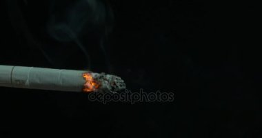 Yanan sigara duman siyah arka plan ile. Sigara siyah bir arka plan karşı ışıklı. Sigara yaktı. Kül tablası üzerinde sigara closeup güzel küçük bir duman ile