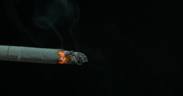 Brûler la cigarette avec de la fumée sur fond noir. Cigarette éclairée sur un fond noir. La cigarette a brûlé. Gros plan de cigarette sur cendrier avec un beau brin de fumée 