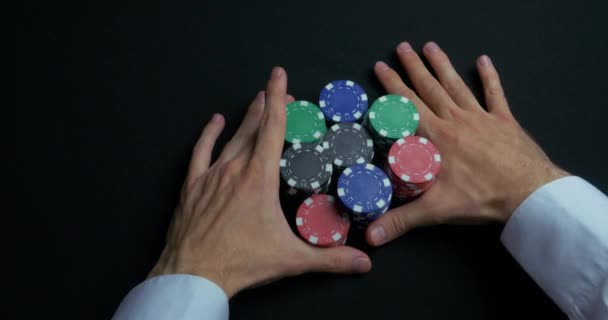 Пачка фишек для покера и две руки на столе. Крупный план фишек для покера в стопках на зеленой поверхности стола фетровой карты. Покерные фишки и руки над ним на зеленом столе. Дилер — стоковое видео