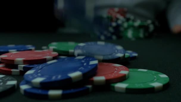 Close-Up of Man Jogando um Poker Chips em câmera lenta. Close-up de mão com jogar fichas de jogo no fundo preto. Jogador de poker aumentando suas apostas jogando fichas na mesa de jogo . — Vídeo de Stock