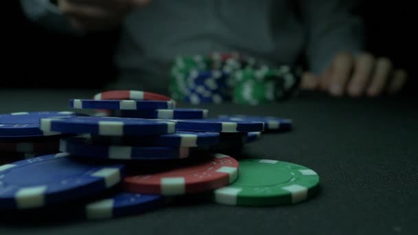 Μεγέθυνση του ανθρώπου που ρίχνει μια μάρκες πόκερ σε αργή κίνηση. Γκρο πλαν του χεριού με ρίψη τυχερών παιχνιδιών μάρκες σε μαύρο φόντο. Αύξηση του πονταρίσματος ρίχνοντας τις μάρκες στο τραπέζι παιχνιδιού παίκτη του πόκερ. — Αρχείο Βίντεο