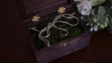 Alyans mezarda masanın üzerine yosun dolu. Doğal çiçek gelin gelin buketi yakınındaki alyans yalanlarla ahşap kutu