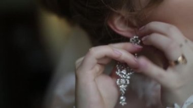 Güzel gelin küpe üzerinde koyar. Güzellik modeli kız takı evlilik için giyiyor. Düğün kadın portre. Kadın kıvırcık saç ve dantel örtü ile. Takı ve güzellik kavramı - giyen yakın