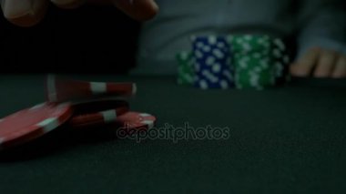 Poker fişleri ve yeşil masa üstündeki elleri. Blackjack Casino, bir adam bir bahis yapar ve bir çip koyar. Yeşil masada iki eli ve poker fişleri yığını.