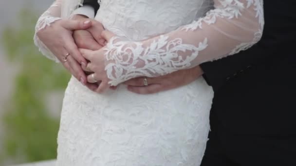 Bruden håller en brudbukett i händerna, brudgummen kramar henne bakifrån. brudgummen kramas bruden bakifrån — Stockvideo