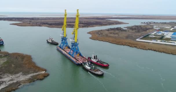 Guindastes de reboque para contentores. Navio grande contentor puxado por rebocadores. Vista aérea de cima para baixo. Navio de carga de contêiner com ponte de guindaste de trabalho no estaleiro ao entardecer para exportação de importação logística — Vídeo de Stock