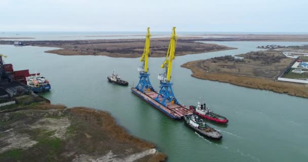 Trekkende kranen voor containers. Grote containerschip getrokken door sleepboten. Top-down luchtfoto. Container-lading vracht geleverd met kraan brug in scheepswerf werken in de schemering voor logistieke Import Export — Stockvideo