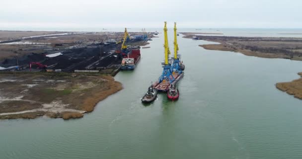 Trekkende kranen voor containers. Grote containerschip getrokken door sleepboten. Top-down luchtfoto. Container-lading vracht geleverd met kraan brug in scheepswerf werken in de schemering voor logistieke Import Export — Stockvideo