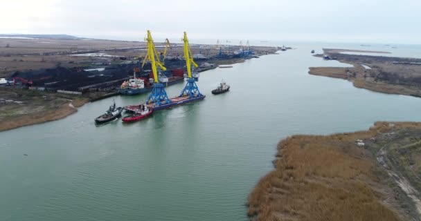 Trekkende kranen voor containers. Grote containerschip getrokken door sleepboten. Top-down luchtfoto. Container-lading vracht geleverd met kraan brug in scheepswerf werken in de schemering voor logistieke Import Export — Stockvideo