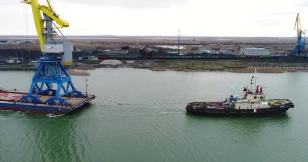 Guindastes de reboque para contentores. Navio grande contentor puxado por rebocadores. Vista aérea de cima para baixo. Navio de carga de contêiner com ponte de guindaste de trabalho no estaleiro ao entardecer para exportação de importação logística — Vídeo de Stock