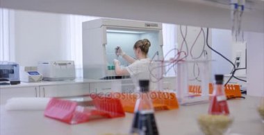 Genç bilim adamı modern Biyoloji laboratuarında çalışıyor. Bir test tüpünde bir laboratuvar açık çözüm onun yanında onun mikroskop ile bakarak kadın tıbbi ya da bilimsel araştırmacı veya kadın doktor.