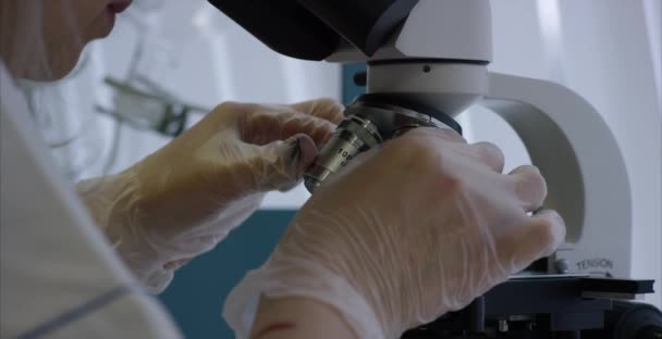 Clinicien sérieux étudiant l'élément chimique en laboratoire. Gros plan de la lentille microscopique. Échantillon dans la lame de microscope préparé pour l'analyse en micro 