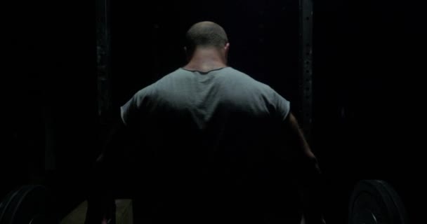 Entraînement d'haltérophilie. Homme musclé confiant s'entraînant squats avec des cloches au-dessus de la tête. Gros plan portrait d'entraînement bodybuilder professionnel avec haltère à la salle de gym. Vue de derrière, Silhouette. Gros plan — Video