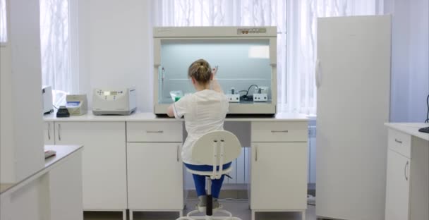 Unga kvinnliga nutritionist provning mat prover i laboratorium. Kvinnliga forskare som arbetar på en dator i ett laboratorium. Professionella kvinnliga forskare undersöker medicinska prover bakifrån — Stockvideo