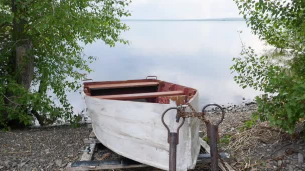 Old rowing fishing boat are tied and marooned with chain to the river shore. — Stock Video