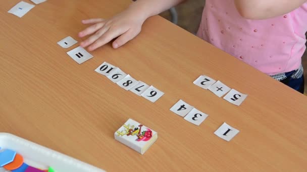 A mathematical example. Child holds a paper figure. Mathematical problem solving in primary school. — Stock Video