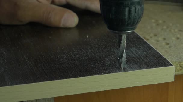 大工便利屋木工ワーク ショップ テーブルの上の板に穴をあける電動ドリルを使用しています。ドリル穴、スローモーションになります — ストック動画