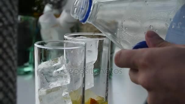 Выливаю воду из бутылки в стакан. Подготовительный коктейль, замедленная съемка — стоковое видео