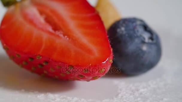 Geschnittene Erdbeeren und Blaubeeren aus nächster Nähe. Erdbeere und ihre Hälfte auf weißem Hintergrund. Kuchen und Dekoration mit frischen Beeren — Stockvideo
