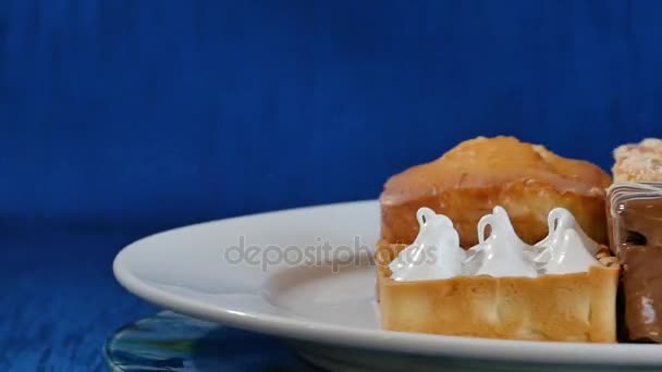 Bolos com cereja em uma chapa branca em tábuas de madeira. pastelaria diferente. Bolos — Vídeo de Stock