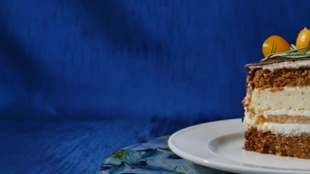 Delicioso pastel de chocolate en el plato en la mesa sobre fondo azul oscuro. Un trozo de pastel de chocolate con crema de vainilla. Gotas de chocolate — Vídeos de Stock