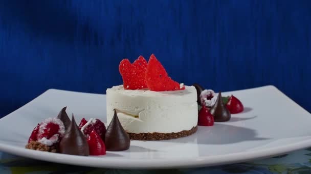 Cake met frosting meringue en frambozen. Schuimgebak Pavlova cake met verse frambozen en bosbessen op een donker blauwe achtergrond. Grote meringue zephyr op plaat — Stockvideo