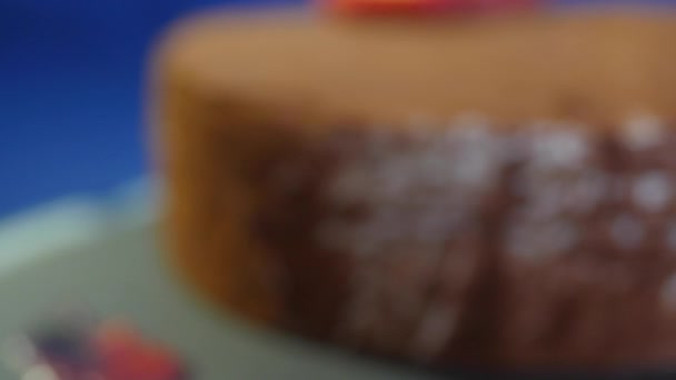 Close-up de bolo de chocolate caseiro com morangos no fundo azul escuro. Sobremesa de chocolate. Bolo de morango fresco com cobertura de chocolate em uma mesa — Vídeo de Stock