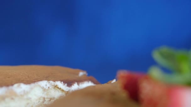 Nahaufnahme von hausgemachtem Schokoladenkuchen mit Erdbeeren auf dunkelblauem Hintergrund. Schokoladenkuchen. Schokoladenkuchen mit Erdbeerscheibe obendrauf — Stockvideo