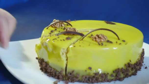 A mão segura uma faca e corta o bolo de mousse verde isolado em um fundo azul escuro . — Vídeo de Stock